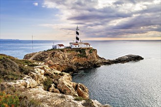 Lighthouse on a cliff with a scenic sea backdrop during sunset, Coastal Hiking tour in the south of