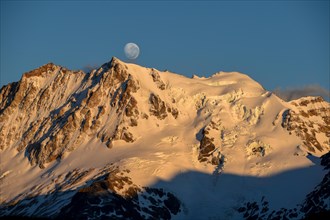 The snow-covered summit of Cerro Hermoso at sunrise with the moon, Perito Moreno National Park,