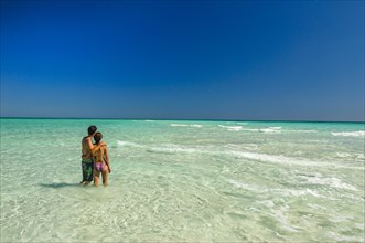 Couple standing in the turquoise water of the island of Nosy Iranja near Nosy Be, Madagascar,