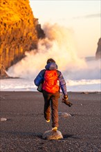 Adventurous photographer woman from behind in winter in Iceland visiting the Reynisfjara Black Sand