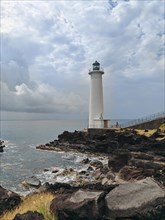 White lighthouse on a steep coast. Dramatic clouds with a view of the sea, pure Caribbean at Le