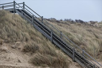 A wooden staircase that leads over the sandy dunes to the beach