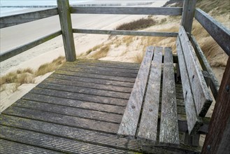 Old wooden bench on a footbridge with a view of the dune landscape
