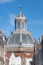 The dome of an old building rises into the blue sky above city buildings, Middelburg, Zeeland,