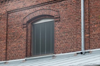 Arched window in a brick building with a traditional tiled roof