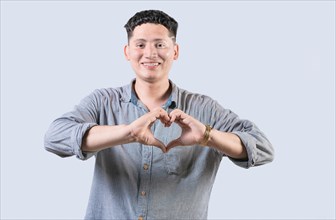 Handsome young man making heart shape with hands isolated. Happy guy making heart shape with hands