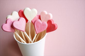 Paper cup with heart shaped pink, red and white popsicles. KI generiert, generiert AI generated