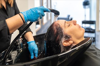 Hairstylist washing the hair of a woman in a sink in a beauty salon
