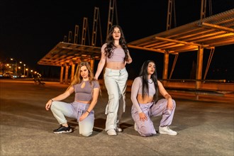 Portrait of three young women forming an urban dance group posing at night
