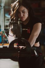 Close-up of a hispanic female mechanic at work, exerting effort on a mechanical piece with