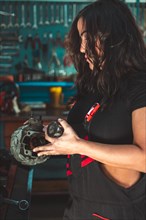 Focused Young confident skilled hispanic sexy female mechanic inspecting a car alternator in an