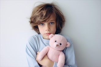 Young boy child with blue swater holding pink teddy bear. Concept for stereotypical colors for