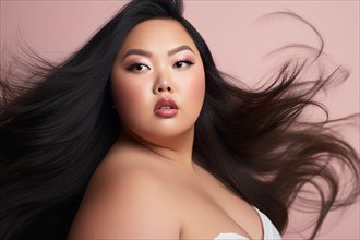 Curvy plus size Asian woman with long black hair in front of pink studio background. KI generiert,
