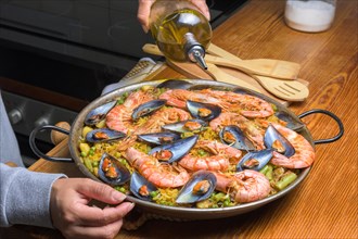Pouring olive oil into a seafood paella, enhancing the flavors of this classic Spanish dish,