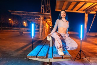 Portrait with copy space of a trap artist posing crouching in an urban park at night
