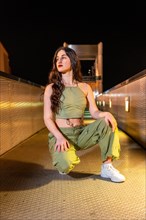 Vertical portrait of a freestyle dancer kneeling posing outdoors at night