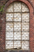 Arched window walled up with visible decay and texture