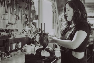 Woman concentrating on mechanical work at a workshop bench, real women performing traditional man
