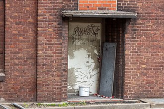 Abandoned doorway with graffiti on a brick wall and signs of decay
