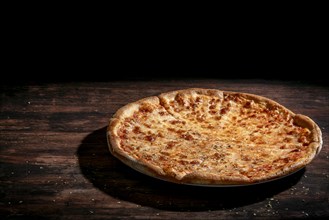 A Margherita pizza against a dark background on a wooden table