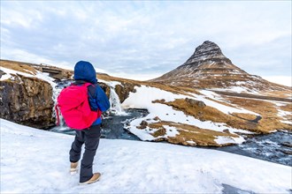Adventurous photographer woman in winter in Iceland photographing in frozen Kirkjufell sunrise