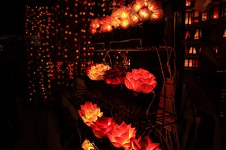 Illuminated lotus flower lamps on a rack at a night street market creating a warm, festive ambiance