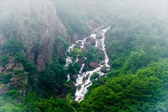 A stunning waterfall with misty waters plunging through rocky cliffs covered in greenery, in South