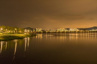 Night scene of lake side park in South Korea with city lights reflecting in the water in Sejeong,