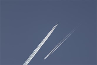 Two jet aircraft passing each other in flight with a contrail or vapour trail behind in the sky,