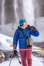 Photographer woman in winter in Iceland visiting Seljalandsfoss waterfall
