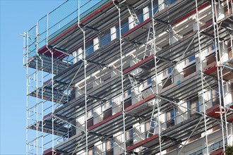 A multi-storey building with scaffolding under a blue sky