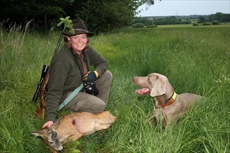 Huntress with hunting dog Weimaraner Shorthair and shot european roe deer (Capreolus capreolus) and