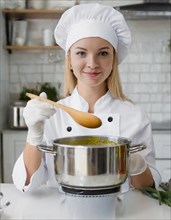 AI generated, An attractive blonde cook with a wooden spoon in the kitchen