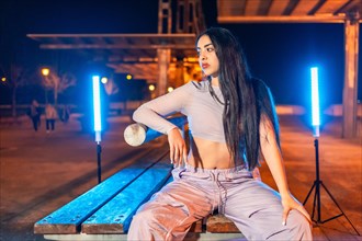 Portrait of a cool hip hop dancer sitting in an urban park at night