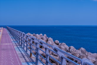 Sea wall and path bathed in blue twilight hues with calm sea waters stretching into the distance,