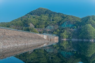 Beautiful lake area with dam and treeline reflected off the calm blue water at Daecheon Lake in
