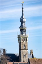 Old tower with a clock and spire rising above lower buildings, Middelburg, Zeeland, Netherlands