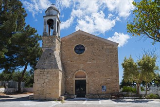 Ancient stone church with a free-standing bell tower under a bright blue sky, Holy Church of Agios