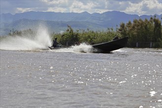 Fast boat travelling at high speed on a river and creating splashing water, Inle Lake, Myanmar,