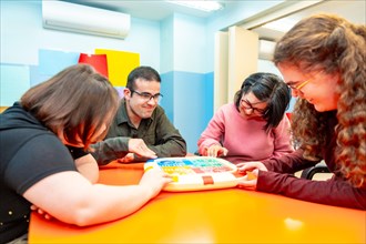 Group of disabled people playing board games together having fun in a day center for people with