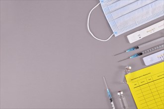 Virus antigen test, vaccine passport, medical face masks, vaccine vials with syringes on gray