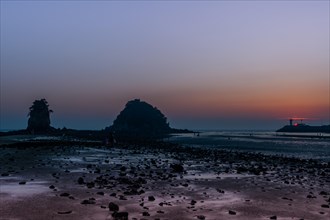 Twilight scene with rock formations on a beach at low tide during sunset, in South Korea