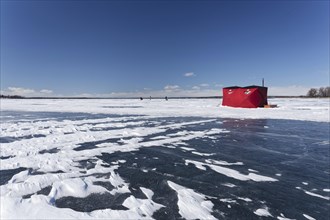 Winter, red fishing hut with snow drifts on a frozen riverscape, Saint Lawrence River, Province of