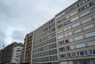 Row of large residential buildings with many windows and balconies on a cloudy day, Blankenberge,