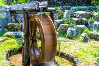Spinning waterwheel by a stone wall demonstrates traditional water harnessing methods, in South