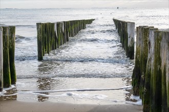 Sea view with waves breaking around wooden piles on the beach
