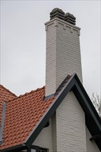 A white chimney on a red tiled roof of a house, DeHaan, Flanders, Belgium, Europe