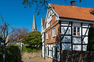 Traditional half-timbered house with church tower in the background on a sunny spring day, Old