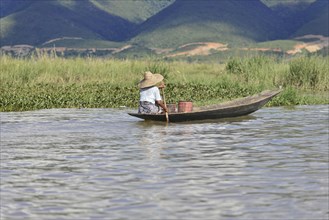 Person rowing alone in a narrow boat on a river, Inle Lake, Myanmar, Asia