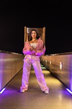 Vertical portrait of an urban teen with pink hip hop style clothes standing posing at night